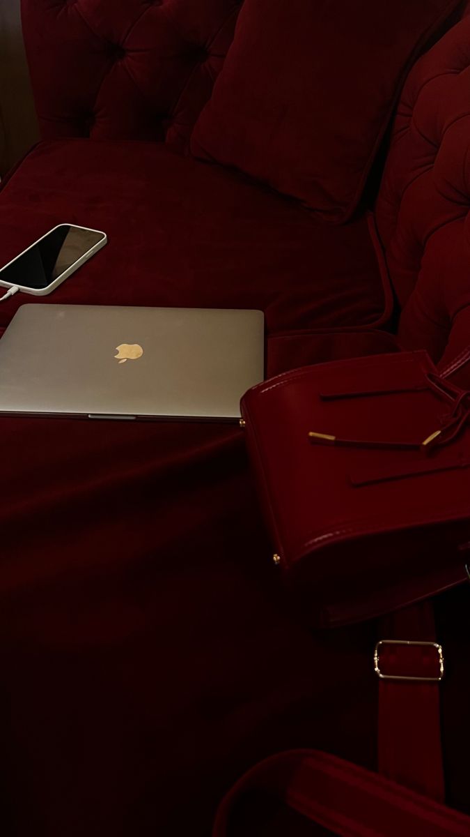 Burgundy velvet sofa with a laptop and a phone